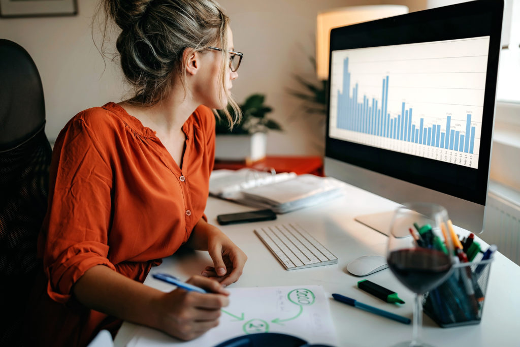 Woman working on desktop at home, writing with green marker