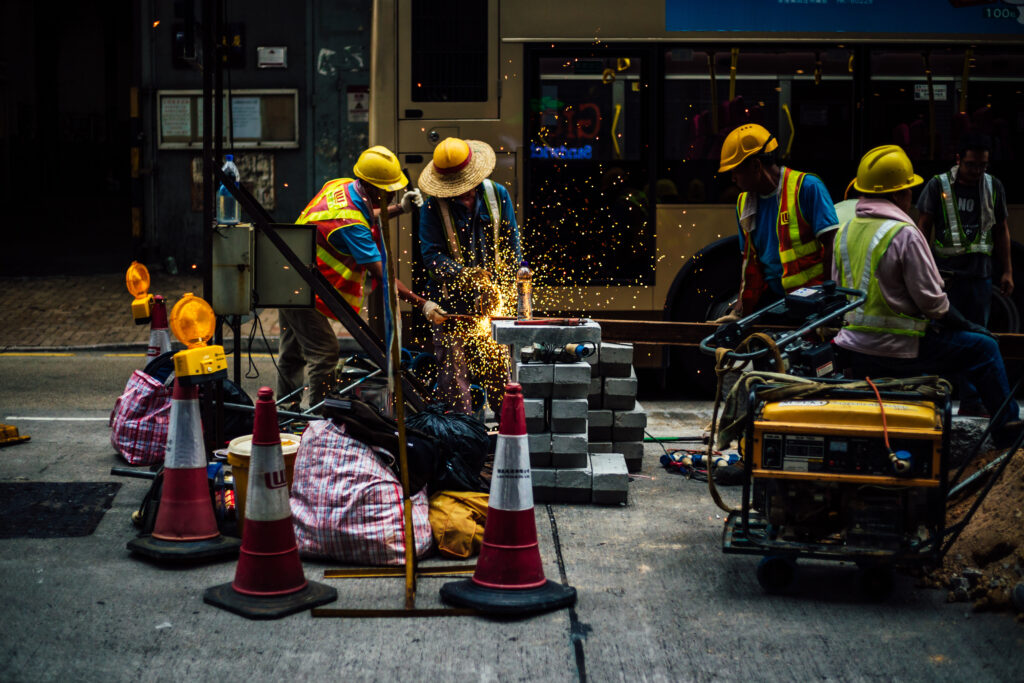 Construction Workers Working On Road Against Bus