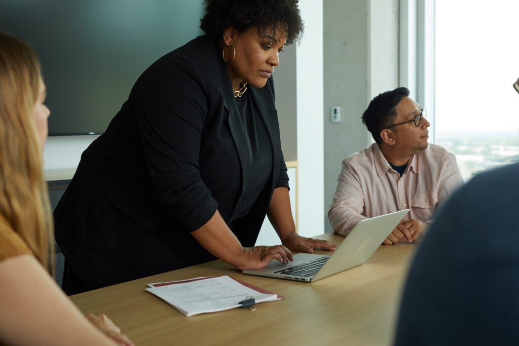 Person standing over laptop during meeting