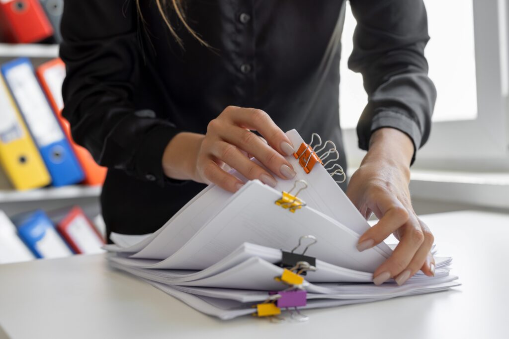 Accountant handling organized financial paperwork and reports but we only see their midsection and hands